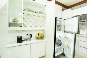 A kitchen with white cabinets, a microwave, a toaster, and a refrigerator.