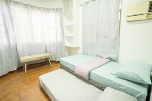 A bedroom with two beds, a bench, and a wardrobe.