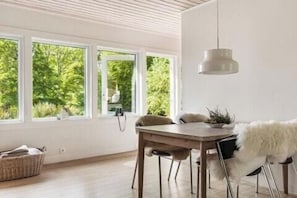 A dining area with a wooden table, chairs, and a hanging light fixture. - Swedish archipelago retreat with sauna in Bökevik (Ronneby)