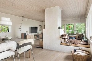 A modern interior with a dining area, a sofa, and a large window. - Swedish archipelago retreat with sauna in Bökevik (Ronneby)