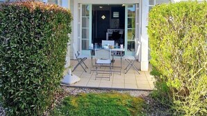 Una casa de dos pisos con un patio, una cocina visible a través del ventanal y un césped bien cuidado.