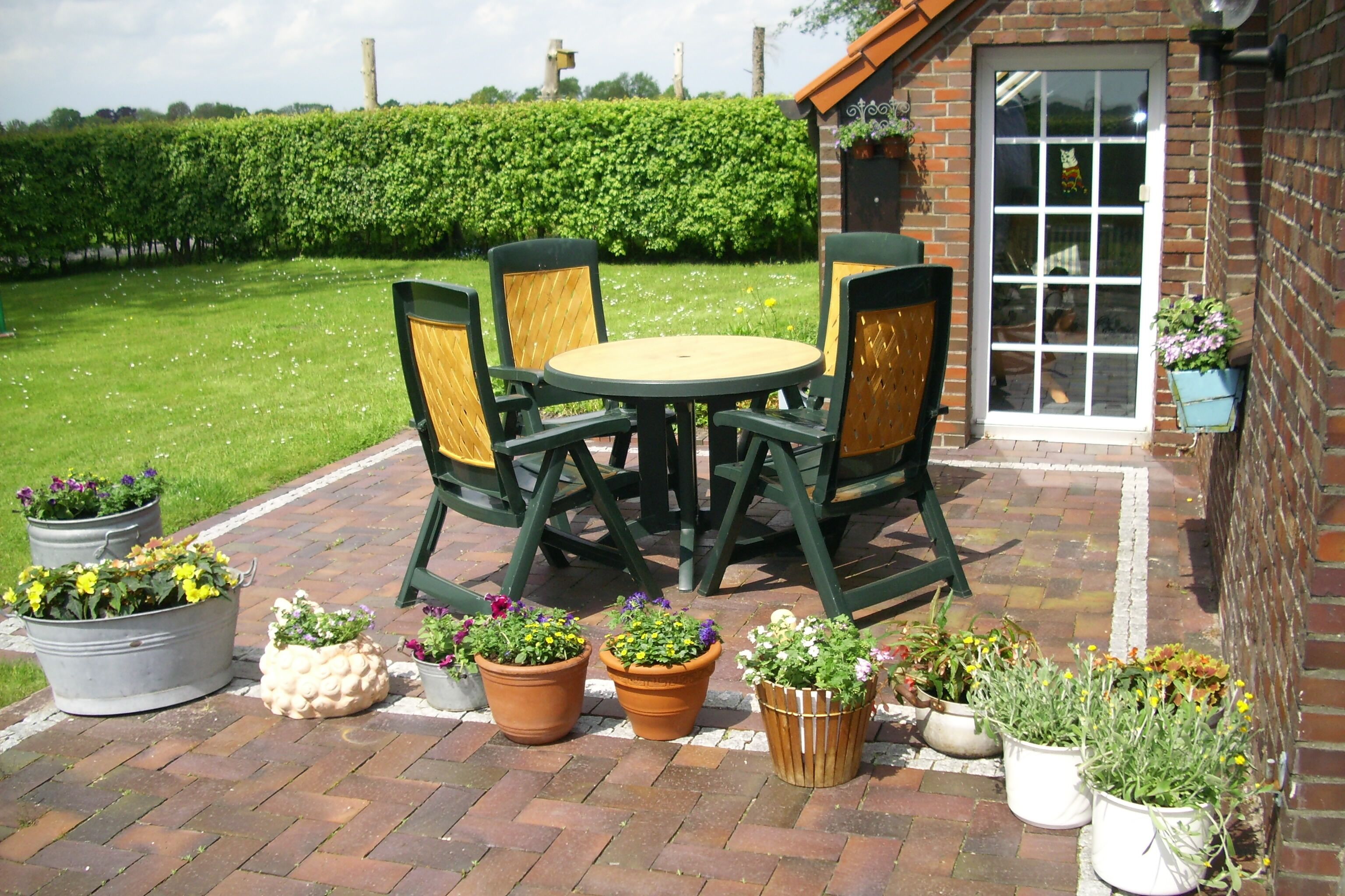 A patio with a table and chairs, surrounded by potted plants.