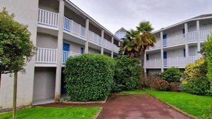 Un hotel de diverses plantes amb balcons, un camí central i vegetació ben cuidada.
