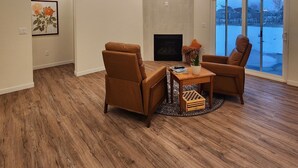 A spacious living room with a fireplace, a television, and a large window with a view of a snowy landscape. - Relax & Recharge in Perham's Lakes Country ~ Family-friendly 3BR Retreat (Perham)