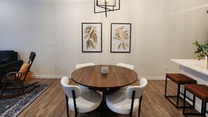 A dining area with a round wooden table, white chairs, a hanging light fixture, and two framed wall art pieces. - Relax & Recharge in Perham's Lakes Country ~ Family-friendly 3BR Retreat (Perham)