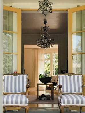 A room with two striped chairs, a chandelier, and a view through a door. - Charming artist's house in Söderåkra (Söderåkra)