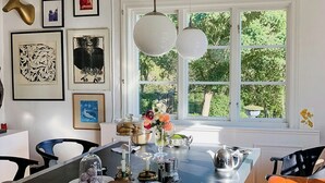 A dining area with a large table, chairs, and a window with a view of greenery. - Charming artist's house in Söderåkra (Söderåkra)