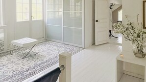 A spacious room with a large sliding door, a bed with a white headboard, a patterned rug, and a vase with flowers on a side table. - Charming artist's house in Söderåkra (Söderåkra)