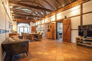 A spacious living area with a high ceiling, wooden beams, a fireplace, and a television. - Historic farmhouse near the Schaalsee lake (Vellahn OT Camin)