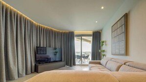 Uma sala de estar moderna com um sofá grande, uma televisão de tela plana e uma varanda com mesa e cadeiras.