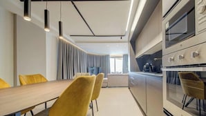 Uma cozinha moderna com mesa de jantar de madeira e cadeiras amarelas, forno embutido e iluminação pendente.