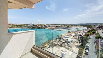 Een balkon met vrij uitzicht over een kustgebied, inclusief een jachthaven en gebouwen.