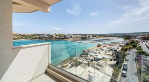 Ein Balkon mit freiem Blick auf eine Küstenlandschaft, darunter ein Yachthafen und Gebäude.