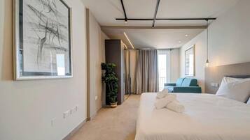 Een moderne hotelkamer met een groot bed, een kamerplant, uitzicht over de stad en een groot abstract schilderij aan de muur.
