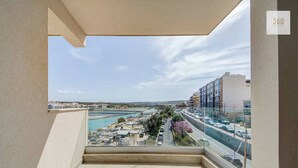 Ein Balkon mit Blick auf eine Küstenlandschaft, darunter eine Straße, Gebäude und ein Gewässer.