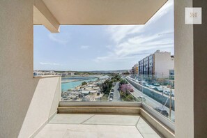 Ein Balkon mit Blick auf eine Küstenlandschaft, darunter eine Straße, Gebäude und ein Gewässer.
