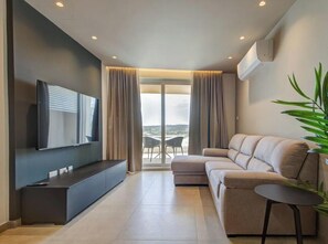 Una sala de estar moderna con un televisor de pantalla plana, un sofá, una mesita y una planta en maceta.