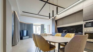 Eine moderne Küche mit Essbereich, ausgestattet mit einem großen Tisch und Stühlen, einem Einbauofen und einem Fernseher.
