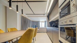 Eine moderne Küche mit integrierten Geräten, eine Essecke mit gelben Stühlen und ein großes Fenster.