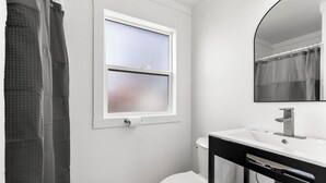 Un baño con inodoro, lavabo, espejo y ventana.