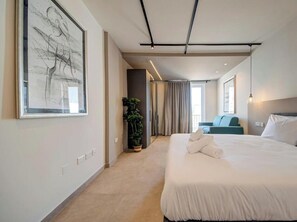 Ein modernes Hotelzimmer mit einem großen Bett, einer Zimmerpflanze und Blick auf den Flur.