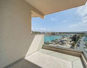 Ein Balkon mit freiem Blick auf die Küstenlandschaft, darunter ein Yachthafen und Gebäude.