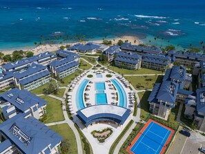 Un complexe hôtelier comprenant plusieurs bâtiments, une piscine centrale et offrant une vue sur la plage.
