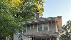 A two-story house with a front porch, a chimney, and a garage. - Quiet College Hill Getaway—Two Kings, Two Queens, remodeled kitchen and Bath (Wichita)