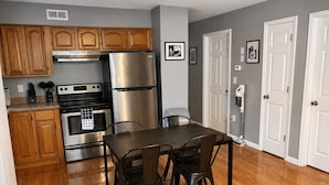A kitchen with wooden cabinets, stainless steel appliances, a dining table with chairs, and a door with a hand dryer. - Close to stadiums and downtown. Pets Welcome: Beautifully remodeled 2 BR Home (Independence)
