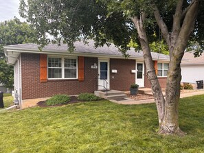 A two-story house with a brick facade, a front porch, and a mailbox. - KC Strong: Beautiful 2 BR Home, Close to stadiums and downtown. (Independence)