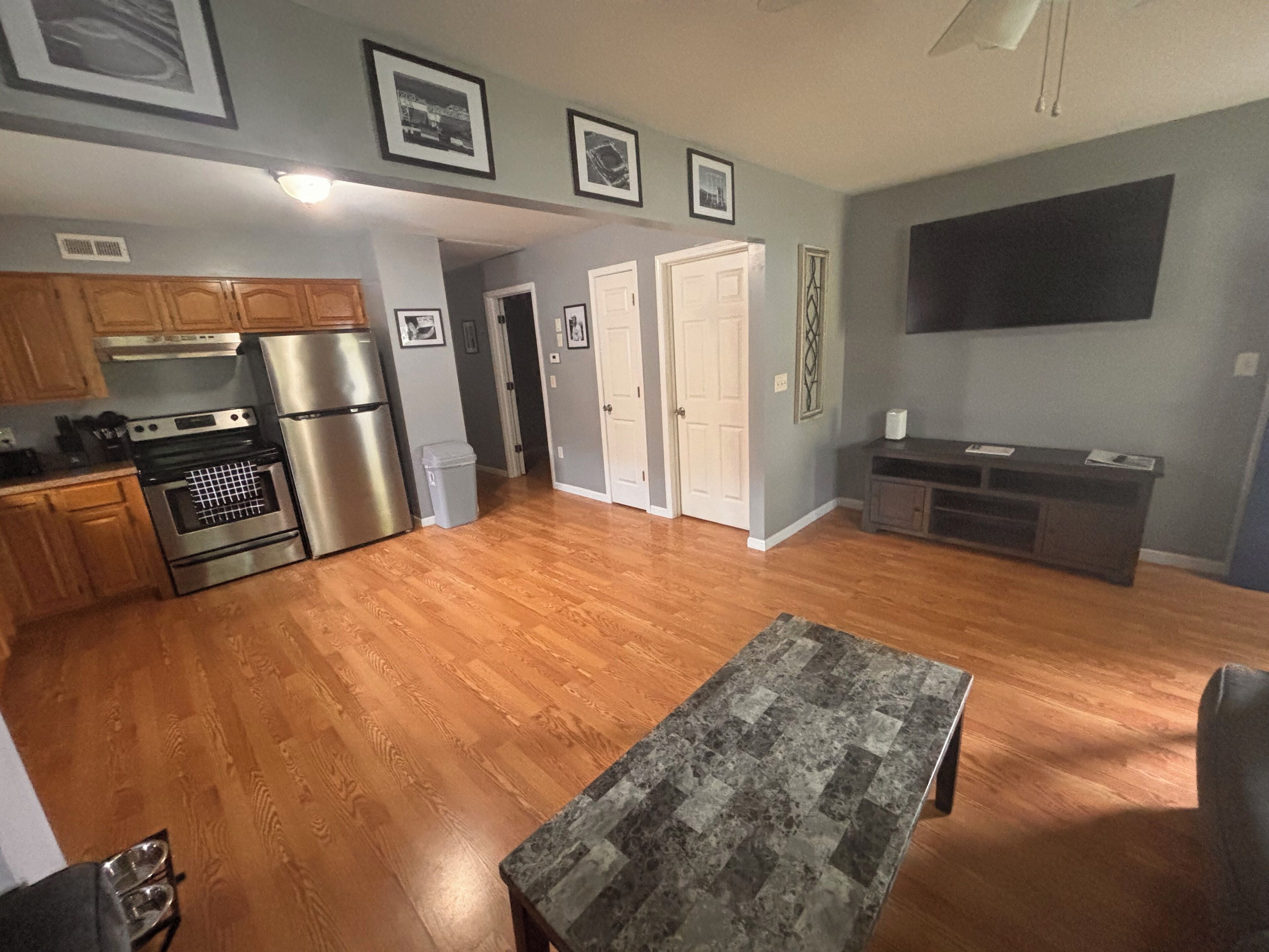 A spacious kitchen with wooden cabinets, stainless steel appliances, and a dining area with a marble table.. KC Strong: Beautiful 2 BR Home, Close to stadiums and downtown.