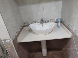Un baño con un lavamanos blanco, un grifo y un dispensador de jabón.