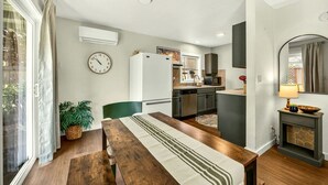 Een moderne keuken met een koelkast, fornuis en een eethoek met een tafel en stoelen.