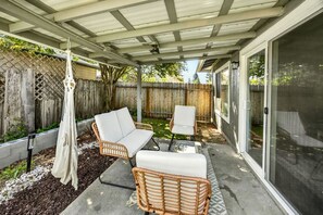 Eine überdachte Terrasse mit Korbmöbeln, einer Schaukel und Blick auf den Garten.
