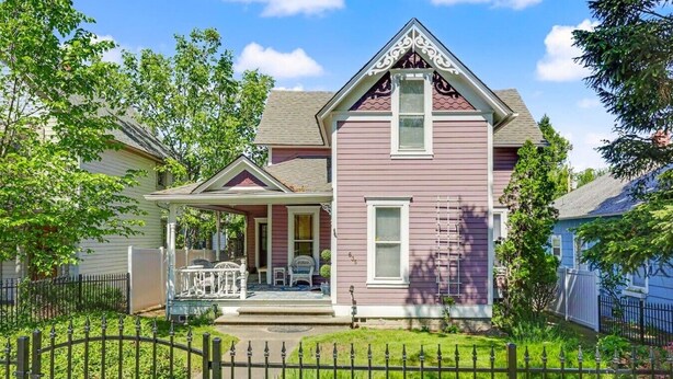 A two-story house with a porch, a small garden, and a metal fence.