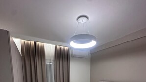 Une chambre d’hôtel moderne équipée d’un lit, de rideaux, d’un climatiseur et d’un luminaire au plafond.