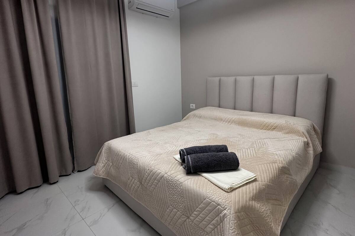 A modern bedroom with a bed, curtains, and a circular ceiling light.