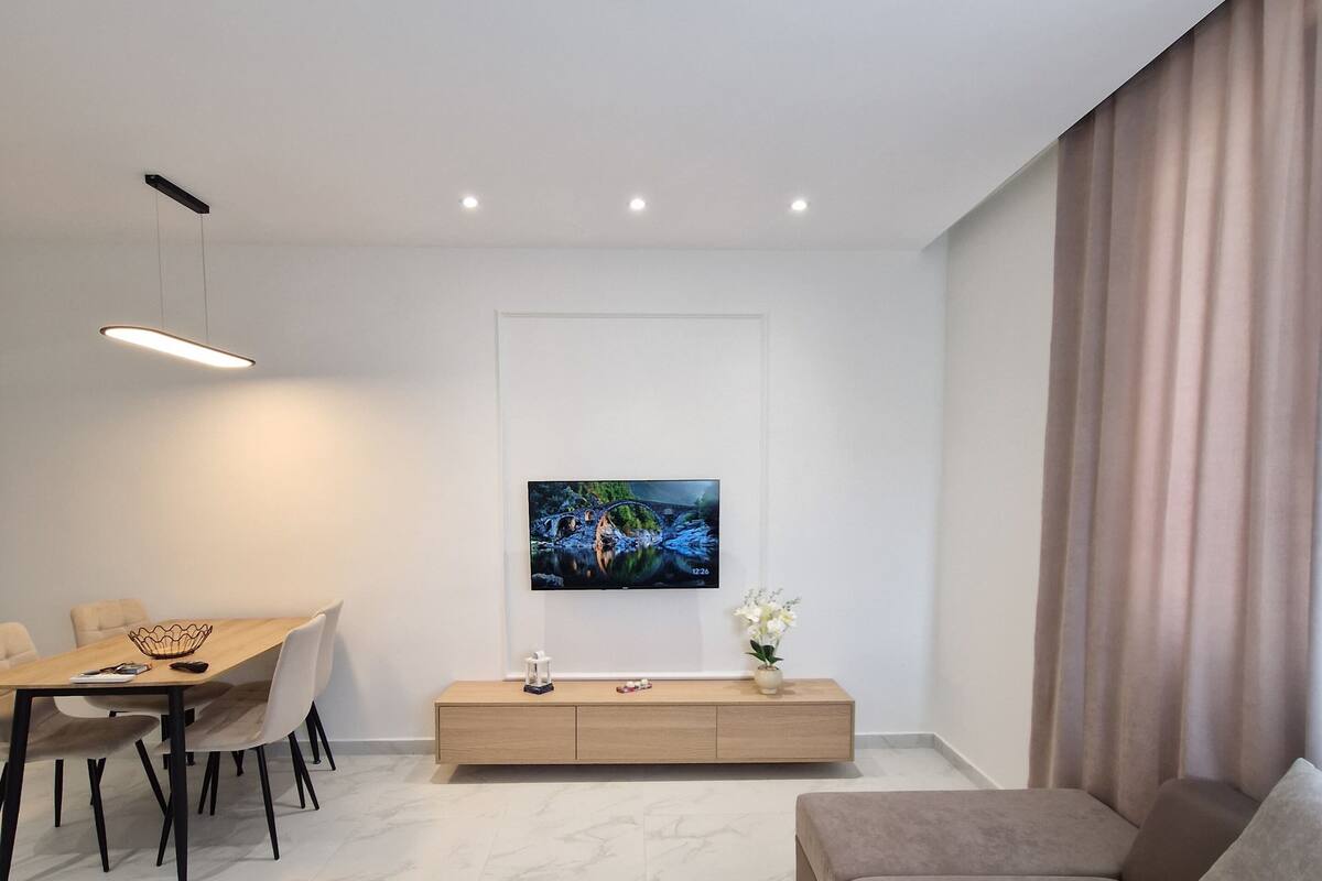A modern living room with a sofa, TV, dining table, and minimalist decor.