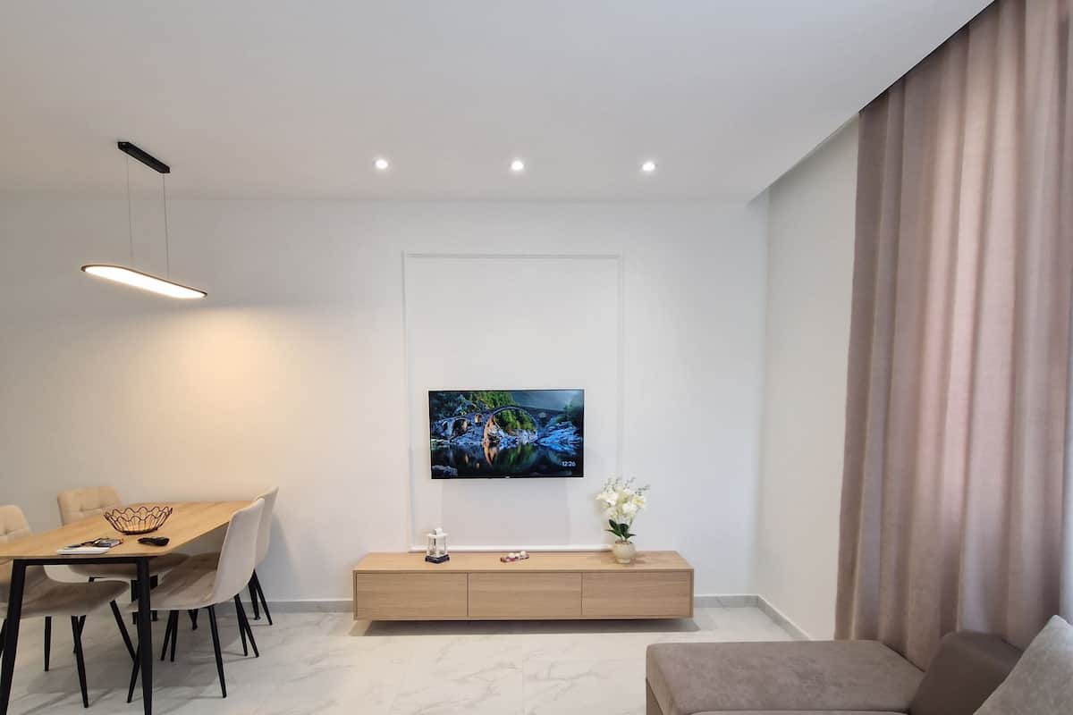 A modern living room with a sofa, TV, dining table, and minimalist decor.