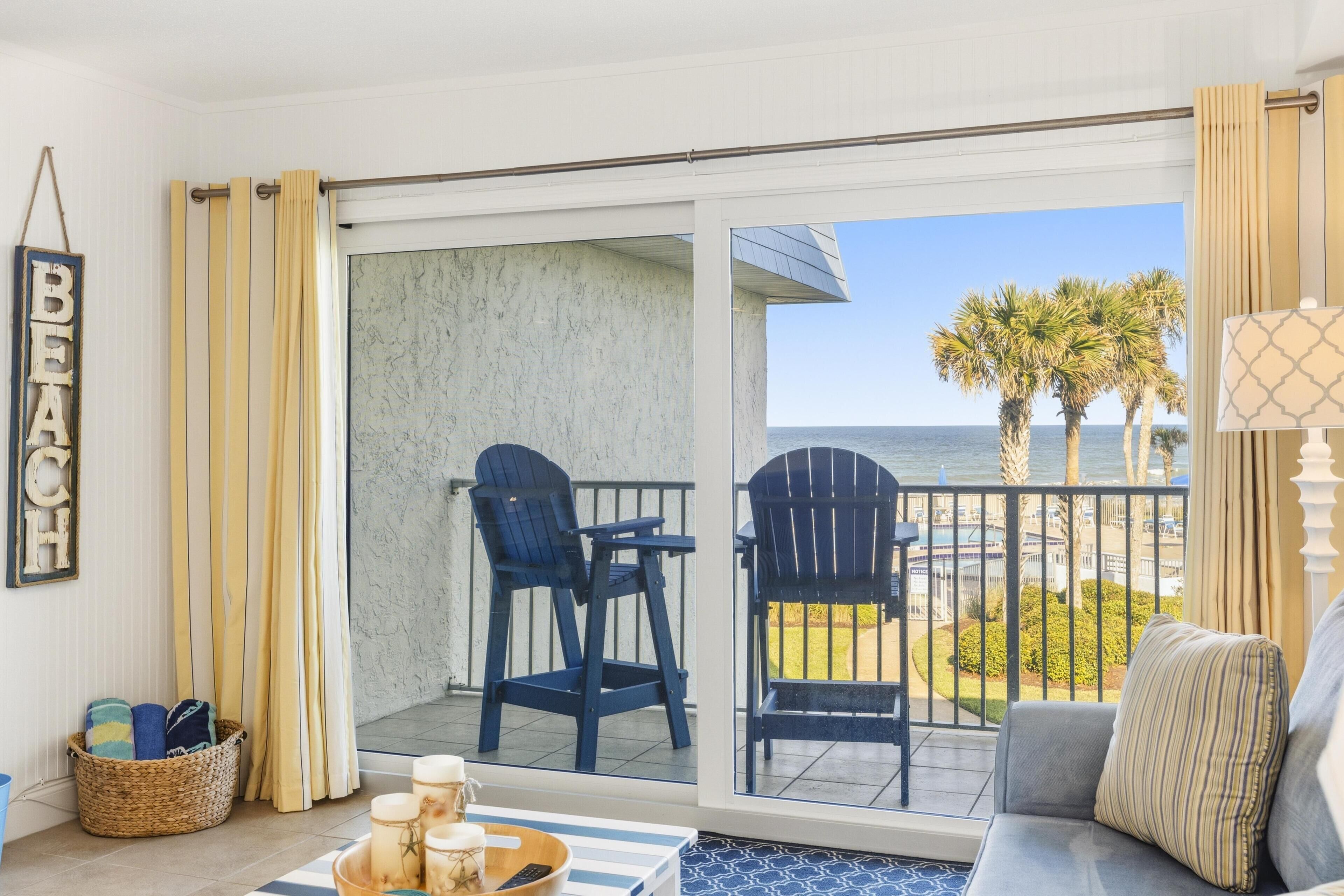 A balcony with two chairs, a wicker basket, and a table with candles.