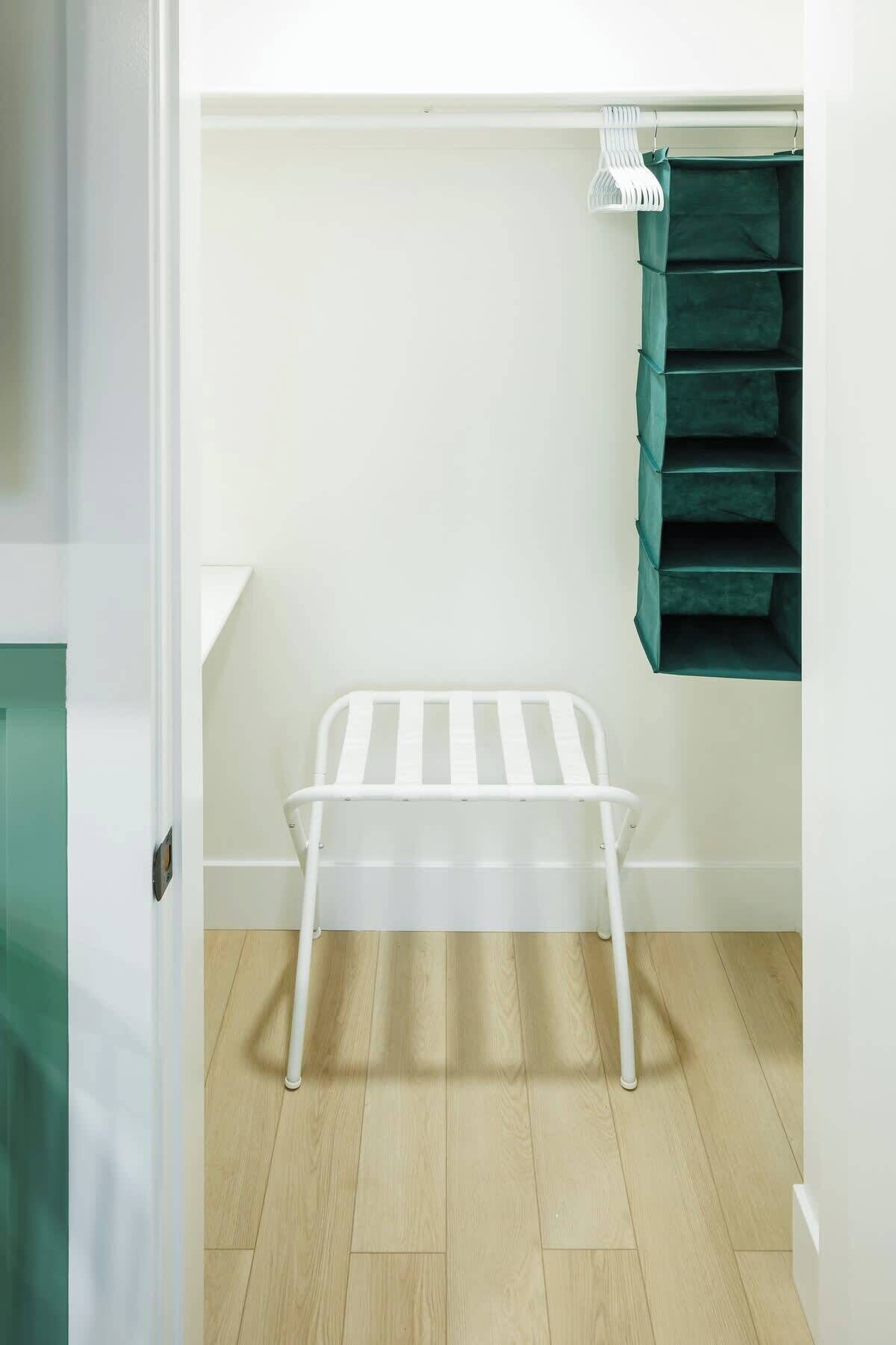 Une pièce avec un banc blanc, un meuble de rangement vert et une porte blanche.