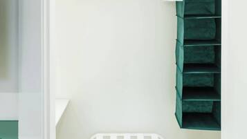 Une pièce avec un banc blanc, un meuble de rangement vert et une porte blanche.