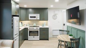 A compact kitchen with a microwave, oven, and a dining area with chairs and a table.