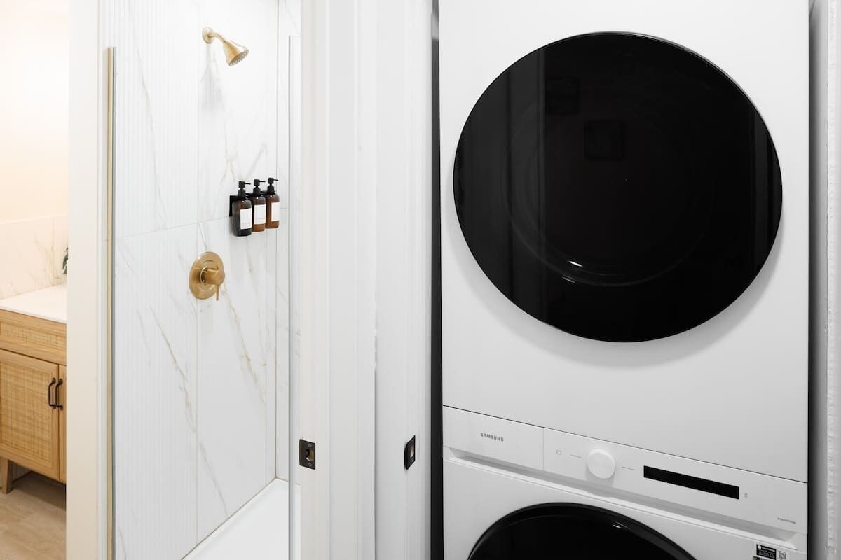 Une buanderie équipée d’un sèche-linge fixé au mur et d’une porte dotée d’une poignée en laiton.