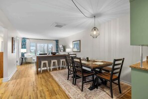 Un comedor con una mesa de madera, sillas y una lámpara colgante.