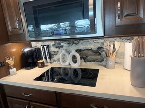 A kitchen with a built-in microwave, a stovetop, and a coffee maker.