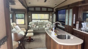 Interior compacto de autocaravana con kitchenette, zona de estar y ventilador de techo.