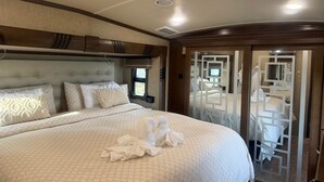 Un dormitorio con una cama grande, un cabecero, una ventana y una puerta que da a otra habitación.
