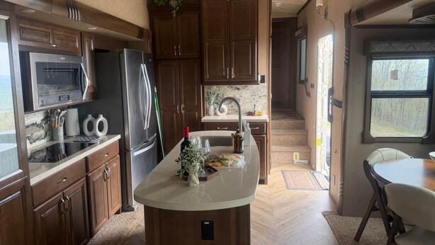 Una cocina compacta con una isla central, armarios de madera, un microondas y un refrigerador.