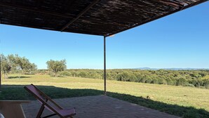 A covered patio with a brick floor, a wooden bench, and a lounge chair. - Spacious 5-bedroom farmhouse in fantastic Alentejo landscape (Bolhas)